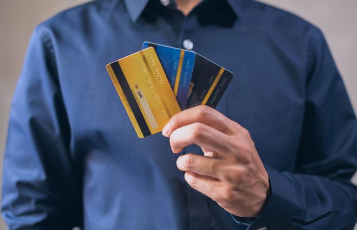 Person holding three credit cards, symbolizing finance, security, and e-commerce.