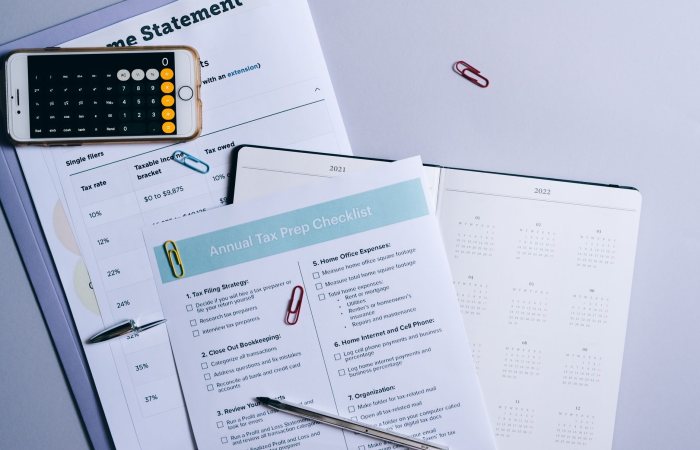 Flat lay of a tax preparation checklist, calculator, and financial documents on a desk.
