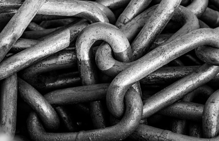 Black and white close-up of industrial steel chains showcasing their texture and strength.