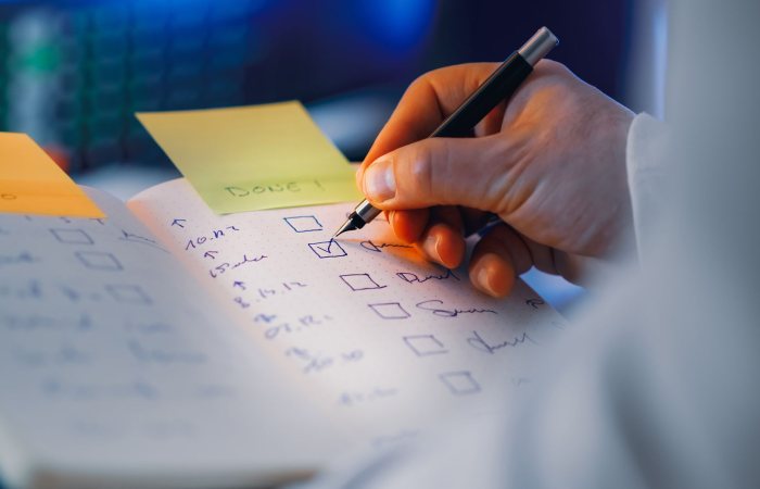 Close-up of a hand writing in a notebook with checkboxes, highlighting productivity and organization.