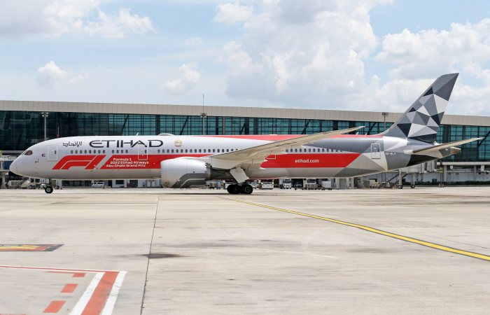 Etihad Airways Boeing 787 with Formula 1 livery parked at a modern airport.