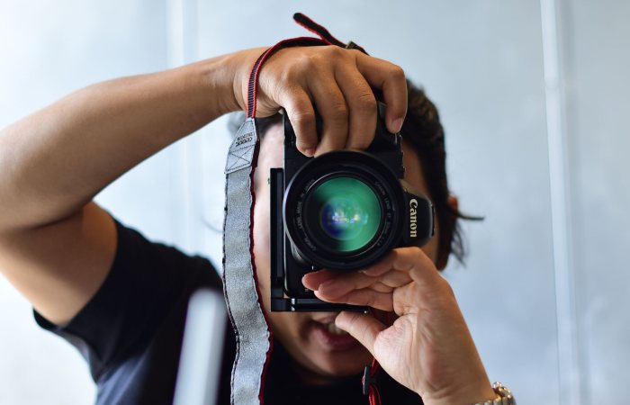 Close-up shot of a photographer with a DSLR camera capturing a photo indoors.