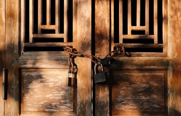 A wooden door with intricate design securely chained with padlocks.