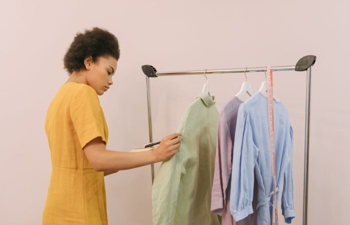 Woman checking clothing items on rack in boutique for inventory.