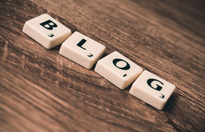 Scrabble tiles spelling 'BLOG' on a wooden background, symbolizing creativity and writing.