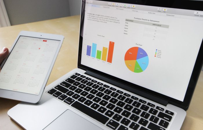 Laptop displaying charts and graphs with tablet calendar for data analysis and planning.