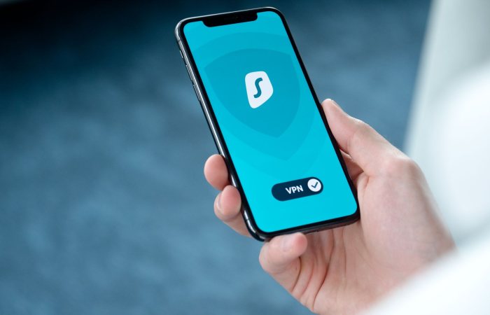 A hand holding a smartphone displaying a VPN app screen for secure online browsing.