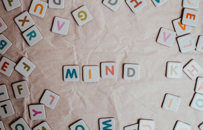 Close-up of scattered letter tiles spelling 'mind' on crumbled paper background.